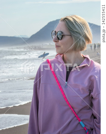 Woman in sunglasses stands on black volcanic sand beside Pacific Ocean at Khalaktyrsky Beach in Kamchatka. Coastal travel, confidence, slow living, freedom, relaxation and connection with nature Woman in sunglasses stands on black volcanic sand beside Pacific Ocean at Khalaktyrsky Beach in Kamchatka. Coastal travel, confidence, slow living, freedom, relaxation and connection with nature 142555411