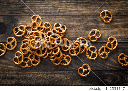 Pretzel mini salted crunchy bretzel snack crackers scattered on dark wooden background table Pretzel mini salted crunchy bretzel snack crackers scattered on dark wooden background table 142555547