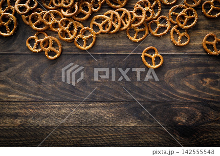 Pretzel mini salted crunchy bretzel snack crackers scattered on dark wooden background table Pretzel mini salted crunchy bretzel snack crackers scattered on dark wooden background table 142555548