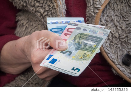 Elderly woman holding euro cash illustrating high winter heating costs and inflation crisis Elderly woman holding euro cash illustrating high winter heating costs and inflation crisis 142555826