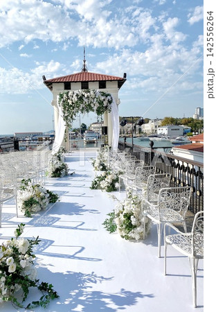 Elegant outdoor wedding ceremony setup by the sea, bright daylight, romantic atmosphere Elegant outdoor wedding ceremony setup by the sea, bright daylight, romantic atmosphere 142556264