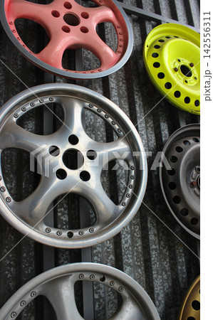 Car rims painted with different colors and protective varnish on the wall of the garage 142556311