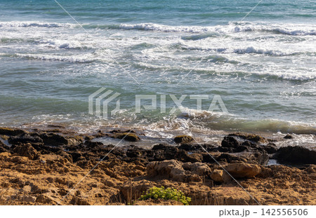 Turquoise sea waves and rocks under the bright sun Turquoise sea waves and rocks under the bright sun 142556506