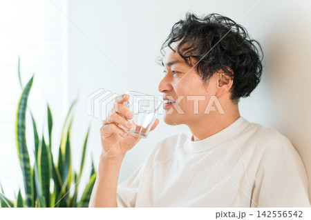 自宅で水を飲み水分補給する爽やかな男性 自宅で水を飲み水分補給する爽やかな男性 142556542