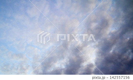 blue sky filled with light soft clouds and a darker cloud on the right blue sky filled with light soft clouds and a darker cloud on the right 142557156