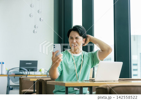 スマホを見て悩む男性 142558522