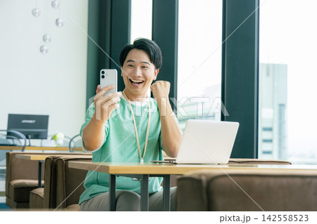 スマホを見てガッツポーズをする男性 142558523