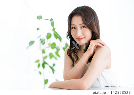 自然光とグリーンに包まれた美肌の40代女性。オーガニック自然派スキンケアの美容イメージ 142558528