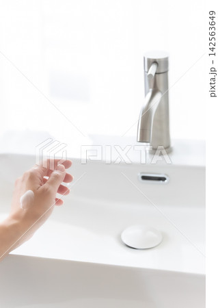 清潔な洗面台で手の甲に保湿クリームを塗る女性の手元・ハンドケア 142563649