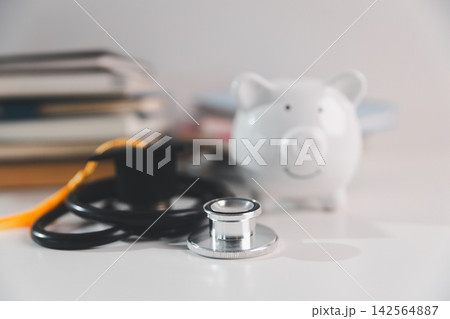 Stethoscope, graduation cap and piggy bank symbolize medical education, healthcare career planning, student savings, tuition expenses, professional development and financial preparation. 142564887