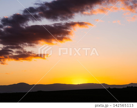 秋の北海道美瑛町の丘の上から見た山裾に沈んだ夕陽の風景 秋の北海道美瑛町の丘の上から見た山裾に沈んだ夕陽の風景 142565113