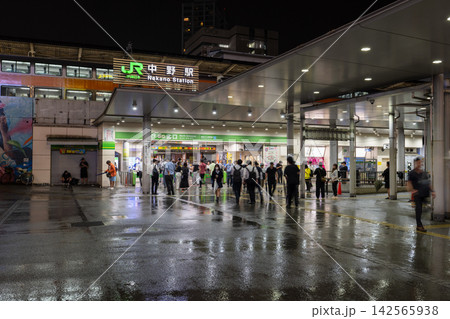 雨の夜のJR中野駅と駅前を行き交う人々の夜景 142565938