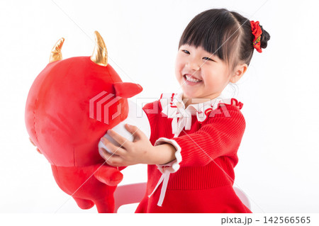 Smiling little girl hugging a red ox plush toy, celebrating the Year of the Ox, Chinese New Year theme. Smiling little girl hugging a red ox plush toy, celebrating the Year of the Ox, Chinese New Year theme. 142566565