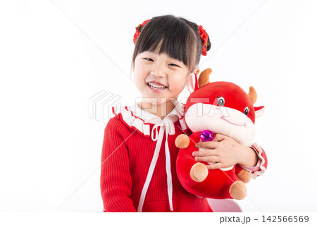 Smiling little girl hugging a red ox plush toy, celebrating the Year of the Ox, Chinese New Year theme. Smiling little girl hugging a red ox plush toy, celebrating the Year of the Ox, Chinese New Year theme. 142566569