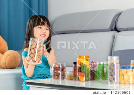 There were many bottled snacks on the table in front of the Asian girl. There were many bottled snacks on the table in front of the Asian girl. 142566601