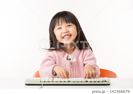 Happy Asian Little Girl Typing on Keyboard and Smiling 142566679