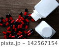 Pills spilling from bottle on wooden table 142567154