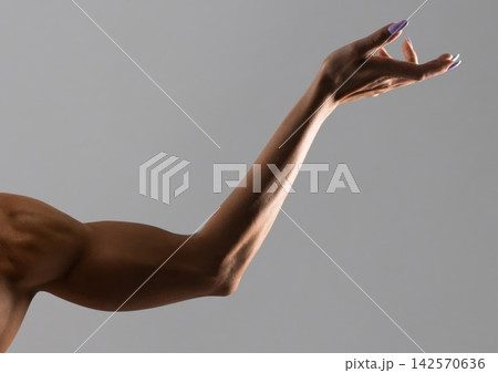 Woman's arm extends upward in studio, with manicured nails 142570636