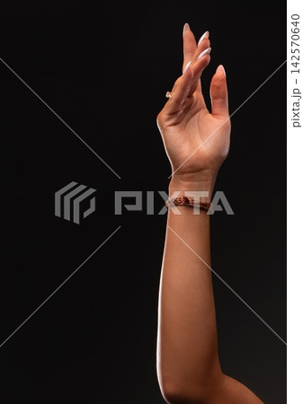 Woman's arm extended with delicate hand gesture on black background Woman's arm extended with delicate hand gesture on black background 142570640