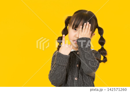 A serious young student covering one eye with her hand while pointing her other pinky finger to the up. A serious young student covering one eye with her hand while pointing her other pinky finger to the up. 142571260
