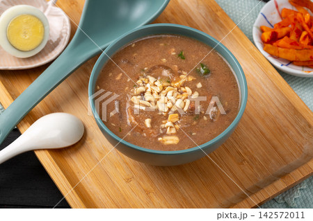 savory Chinese millet porridge Doumo with peanut topping and boiled eggs, overhead shot of traditional breakfast. savory Chinese millet porridge Doumo with peanut topping and boiled eggs, overhead shot of traditional breakfast. 142572011