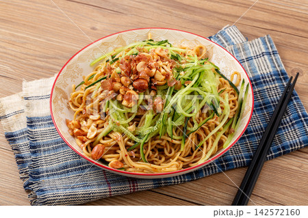 vegetarian cold noodles topped with crushed peanuts and shredded cucumber on a dark table vegetarian cold noodles topped with crushed peanuts and shredded cucumber on a dark table 142572160