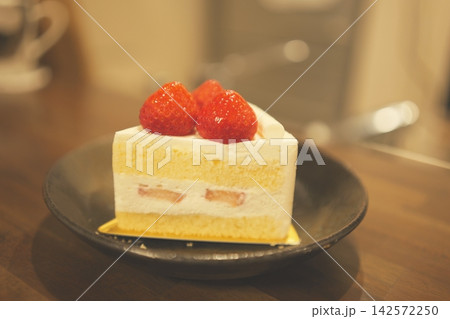 木のテーブルに置かれたカフェ風のイチゴショートケーキ 142572250
