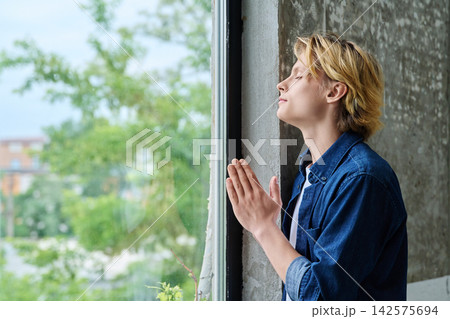 Peaceful teenage student praying with closed eyes Peaceful teenage student praying with closed eyes 142575694