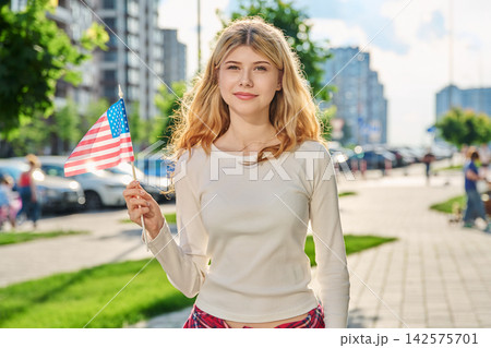 Happy blonde girl holding American flag in the city Happy blonde girl holding American flag in the city 142575701