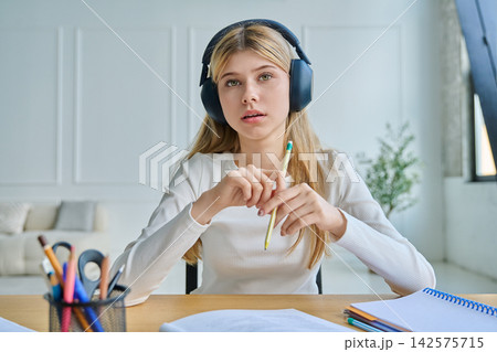 Teenage girl in headphones gesturing during video call 142575715