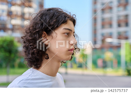 Profile portrait of curly teen boy outdoors Profile portrait of curly teen boy outdoors 142575737