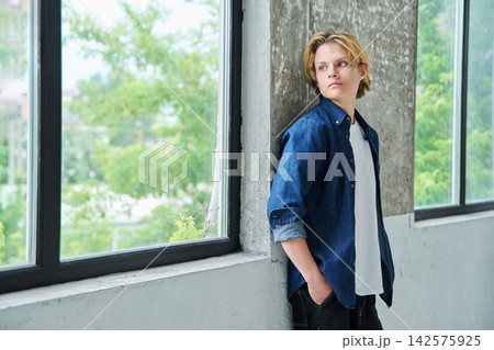 Thoughtful teenage student guy looking out window 142575925