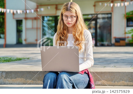 Teenage student working on laptop on school campus Teenage student working on laptop on school campus 142575929