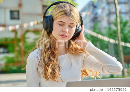 Teenage student listening to audio on campus laptop Teenage student listening to audio on campus laptop 142575931