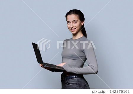 Portrait of smiling teenage girl using laptop on gray background 142576162