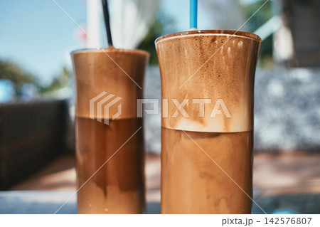 Close up of two refreshing iced coffees with thick foam in tall glasses Close up of two refreshing iced coffees with thick foam in tall glasses 142576807