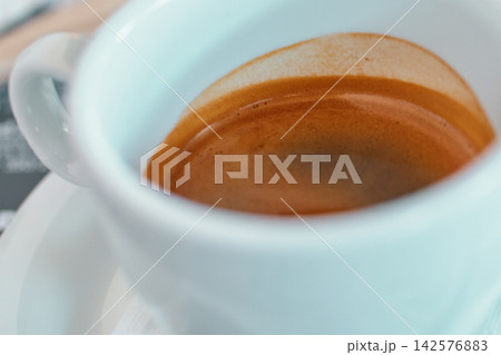 Close-up of a white ceramic cup filled with aromatic fresh espresso coffee Close-up of a white ceramic cup filled with aromatic fresh espresso coffee 142576883
