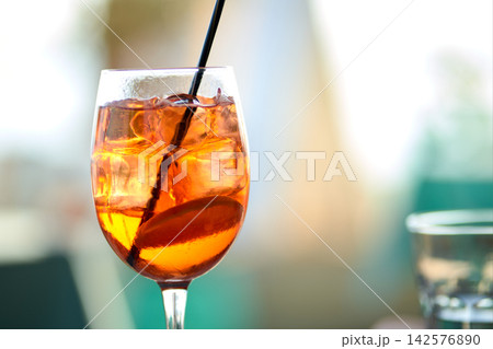 Close-up of a refreshing orange spritz cocktail with ice cubes and a black straw Close-up of a refreshing orange spritz cocktail with ice cubes and a black straw 142576890