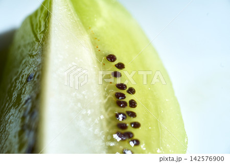 Macro close-up shot of juicy kiwi fruit flesh showing tiny black seeds inside 142576900
