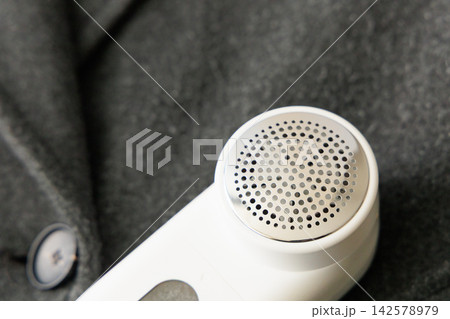 Lint remover placed on fabric showing lint removal process on a clothing item Lint remover placed on fabric showing lint removal process on a clothing item 142578979