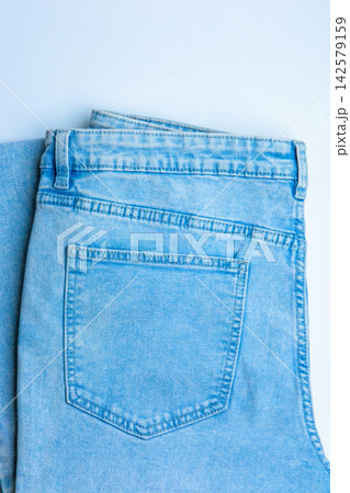 Denim jeans laid flat on a light background showing back pockets and details of the fabric during daylight hours Denim jeans laid flat on a light background showing back pockets and details of the fabric during daylight hours 142579159