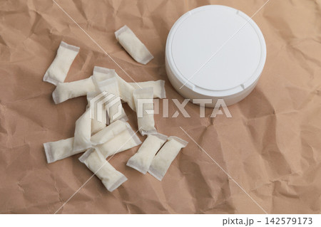 Snus pouches and container placed on crumpled paper with a simple display of nicotine products 142579173