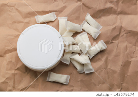 Various snus pouches and a container are seen on crumpled brown paper Various snus pouches and a container are seen on crumpled brown paper 142579174