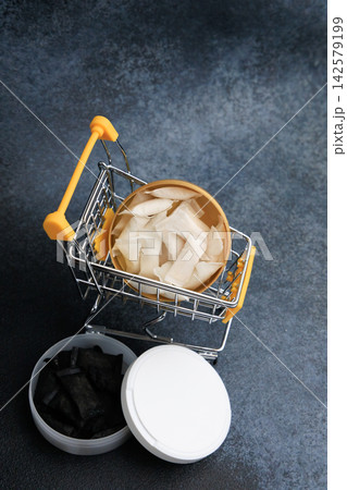 Snus pouches in shopping cart with nicotine pads nearby on a dark surface Snus pouches in shopping cart with nicotine pads nearby on a dark surface 142579199