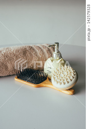 Rolled towel with bamboo brush and soap dispenser on table. Rolled beige towel with bamboo hair brush and ceramic cat soap dispenser on white table, spa accessories and natural materials self care sti Rolled towel with bamboo brush and soap dispenser on table. Rolled beige towel with bamboo hair brush and ceramic cat soap dispenser on white table, spa accessories and natural materials self care sti 142579328