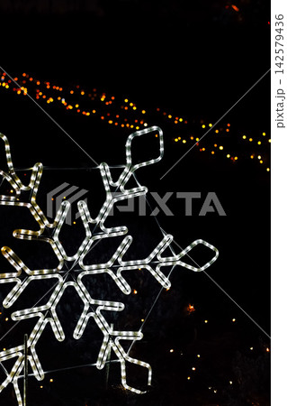 Winter decorations shown as a snowflake light display at night during a holiday celebration in a public park Winter decorations shown as a snowflake light display at night during a holiday celebration in a public park 142579436