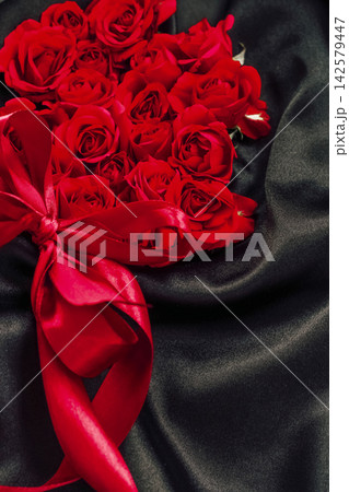 Red roses arranged on black fabric with a red ribbon during a special event 142579447