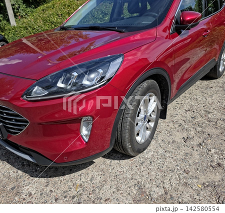 Shiny Red Car Parked on a Sunny Day Surrounded by Lush Greenery 142580554