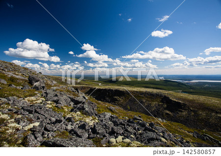 Wide summer landscape from the Khibiny Mountains in Murmansk Region, Russia, showing a rocky mountain slope covered with lichen and low subarctic vegetation above the forested lowlands of the Kola Pen Wide summer landscape from the Khibiny Mountains in Murmansk Region, Russia, showing a rocky mountain slope covered with lichen and low subarctic vegetation above the forested lowlands of the Kola Pen 142580857