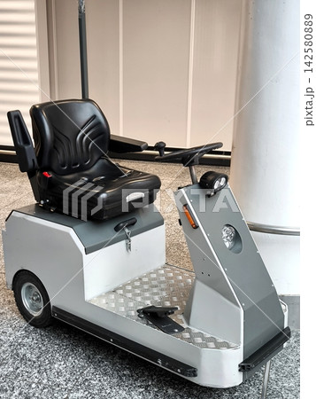 A compact white and gray electric car with a black seat and steering wheel, parked in a modern building interior 142580889